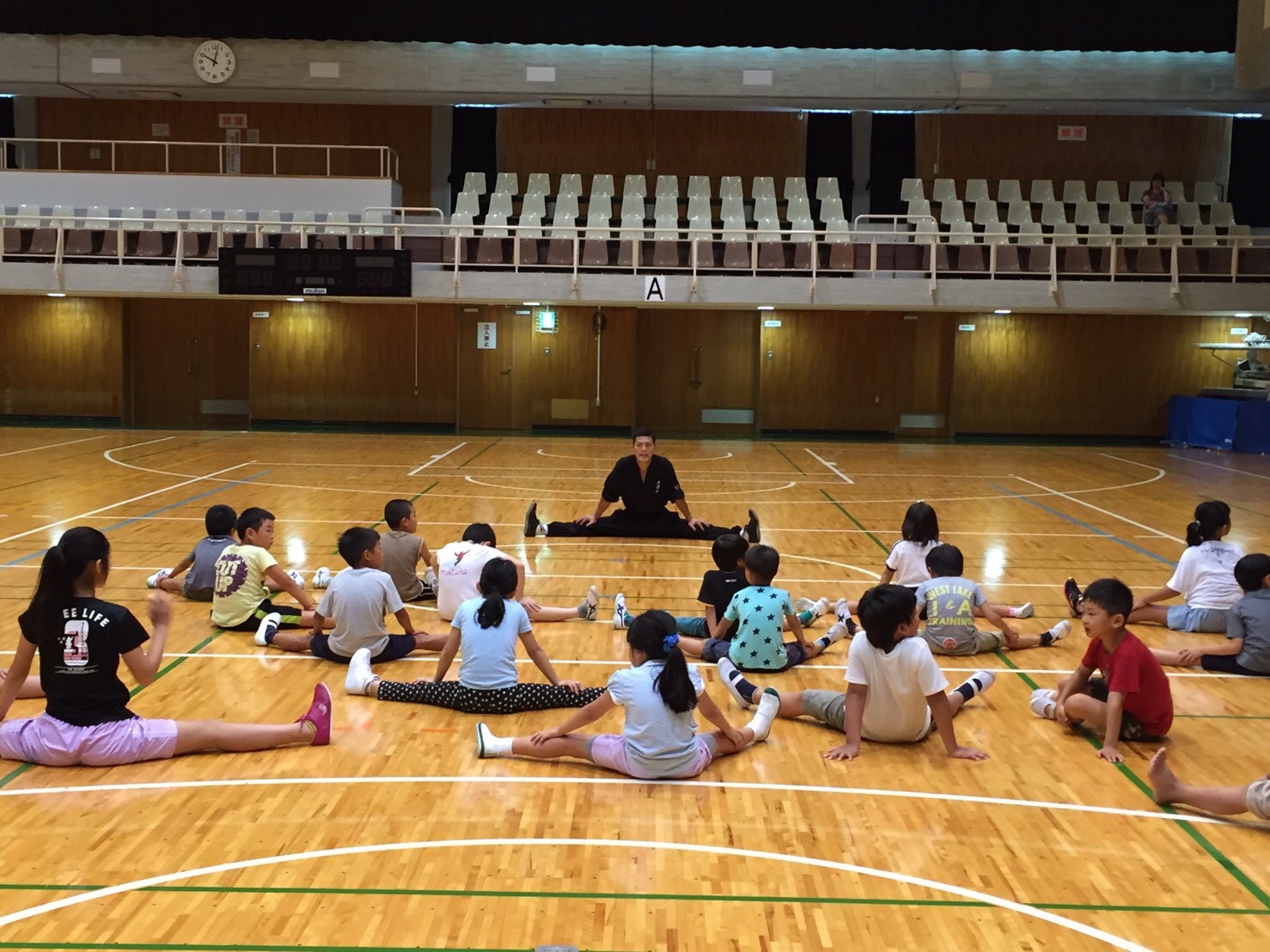 体育館で開脚の稽古をする子どもたち